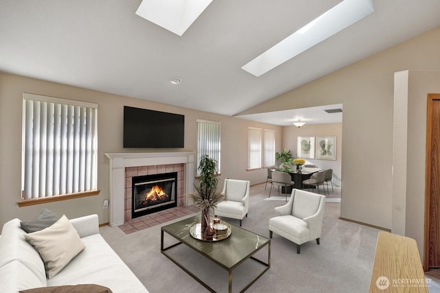 living area featuring a tile fireplace, light carpet, visible vents, baseboards, and lofted ceiling with skylight