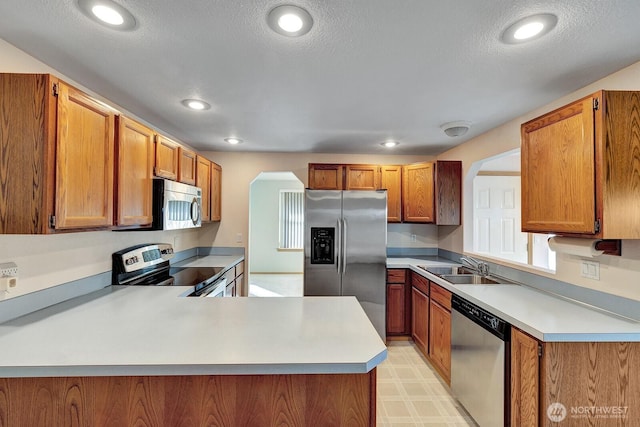 kitchen with stainless steel appliances, light countertops, a sink, and light floors