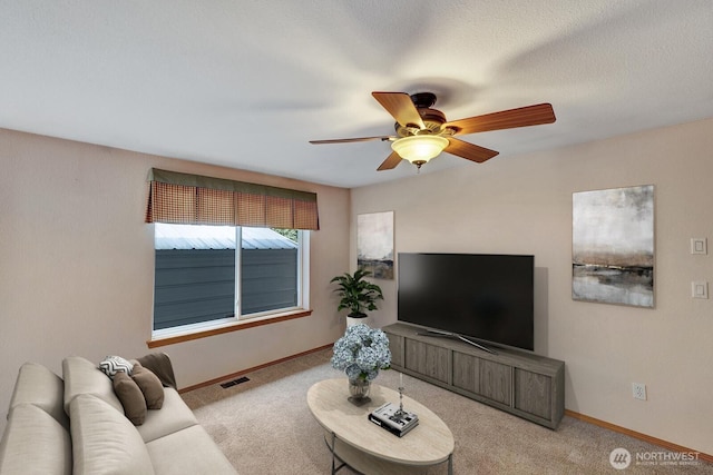 carpeted living area with visible vents, ceiling fan, a textured ceiling, and baseboards