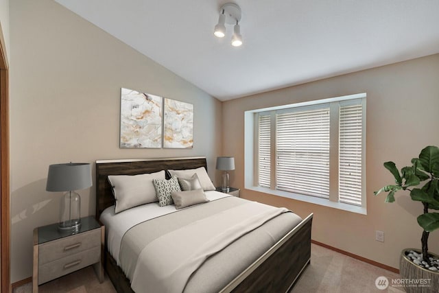 bedroom with baseboards, vaulted ceiling, and light colored carpet