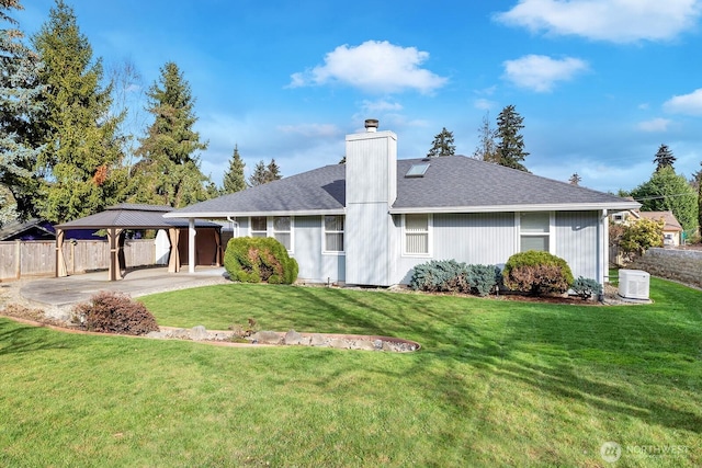 rear view of property featuring a gazebo, a yard, a chimney, and fence