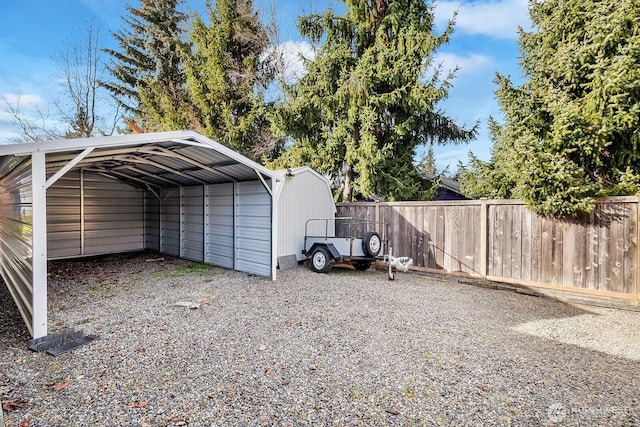 view of parking / parking lot featuring gravel driveway, fence, and a detached carport