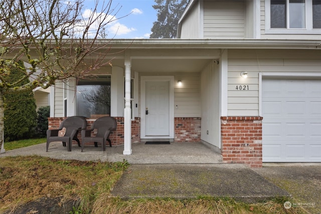 doorway to property with a garage and covered porch