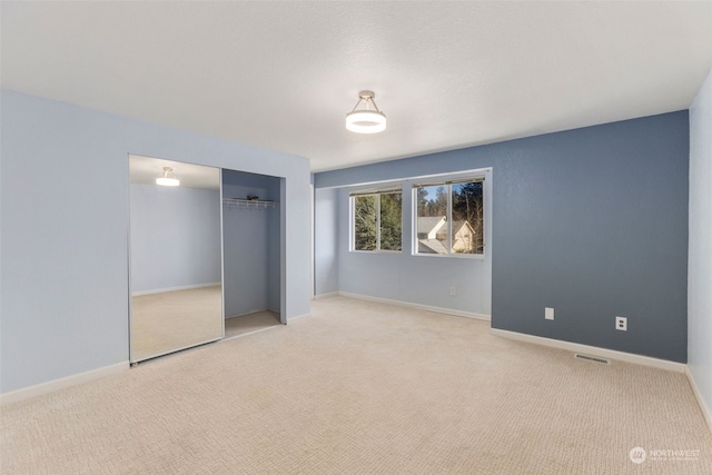 unfurnished bedroom featuring light colored carpet and a closet