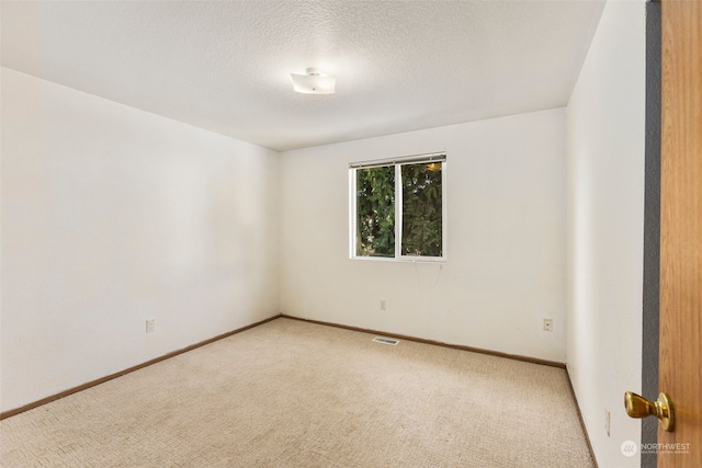 carpeted spare room with a textured ceiling