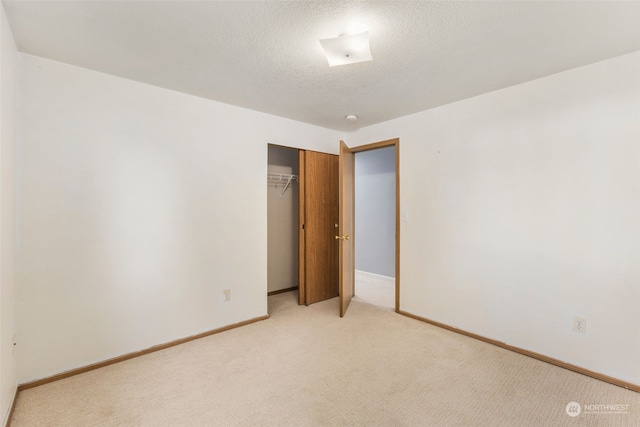 unfurnished bedroom with light colored carpet, a closet, and a textured ceiling