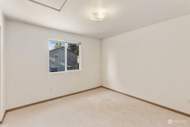 spare room featuring light colored carpet and a textured ceiling