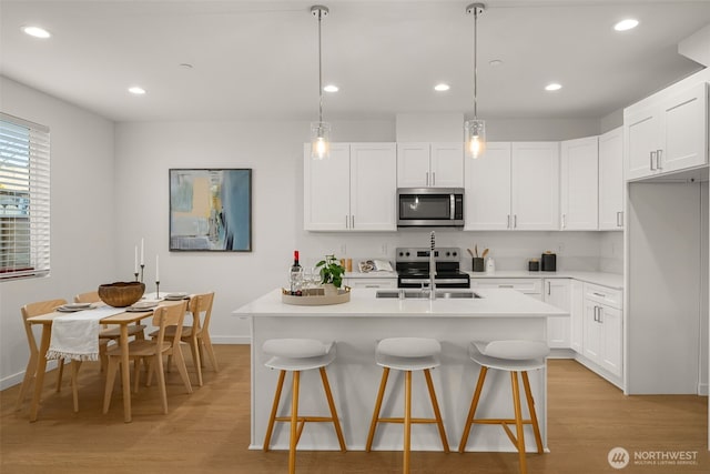 1510E Hollow Dale Pl, Everett, WA 98204 - kitchen featuring stainless steel appliances, light wood-style floors, a breakfast bar area, light countertops, and white cabinets