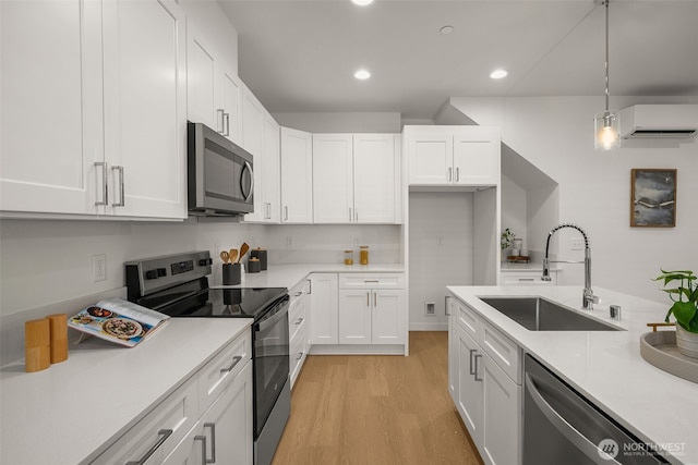 1510E Hollow Dale Pl, Everett, WA 98204 - kitchen with stainless steel appliances, a sink, a wall mounted AC, white cabinetry, and light countertops