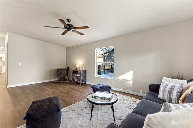 living room with hardwood / wood-style floors, ceiling fan, and a wood stove