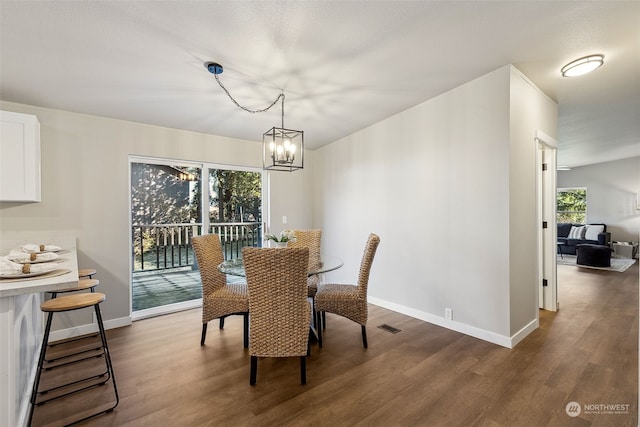 dining area with dark hardwood / wood-style flooring and a notable chandelier