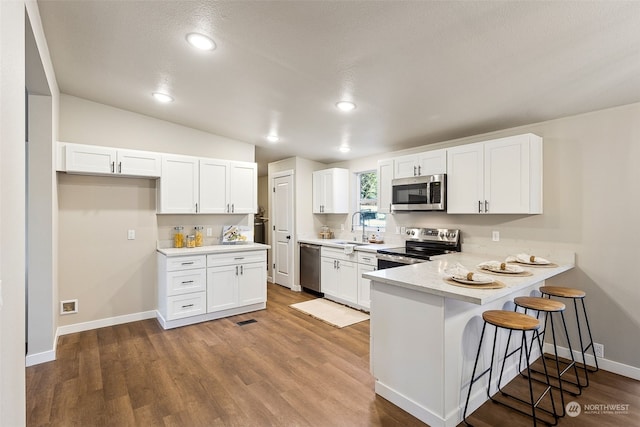 kitchen with sink, a kitchen breakfast bar, stainless steel appliances, white cabinets, and kitchen peninsula