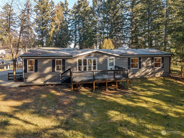 back of property with a deck and a lawn