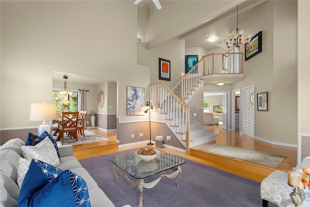 living room featuring hardwood / wood-style flooring, a towering ceiling, beam ceiling, and a chandelier