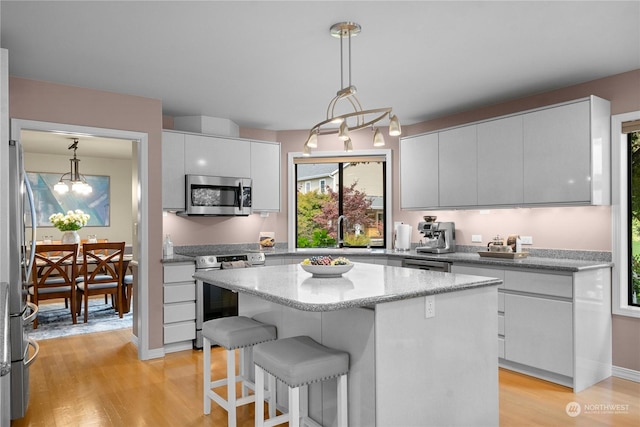 kitchen with pendant lighting, light hardwood / wood-style flooring, white cabinetry, stainless steel appliances, and a center island