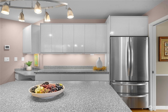 kitchen featuring white cabinetry, hanging light fixtures, and stainless steel refrigerator