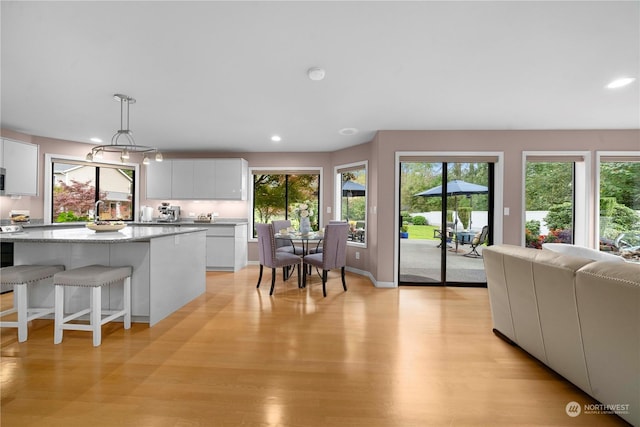 kitchen featuring white cabinetry, a center island, light stone counters, and hanging light fixtures