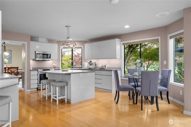 kitchen featuring hanging light fixtures, a center island, white cabinets, and appliances with stainless steel finishes