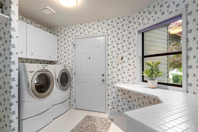 washroom featuring cabinets, light tile patterned flooring, and washer and clothes dryer