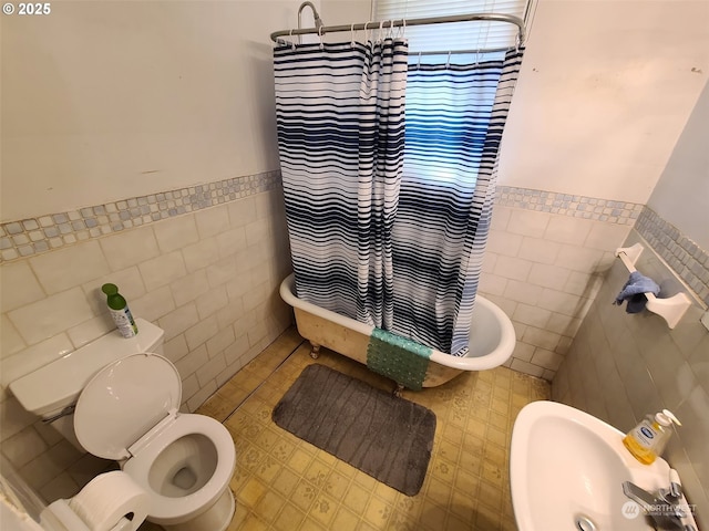 full bathroom featuring toilet, shower / bathtub combination with curtain, sink, and tile walls