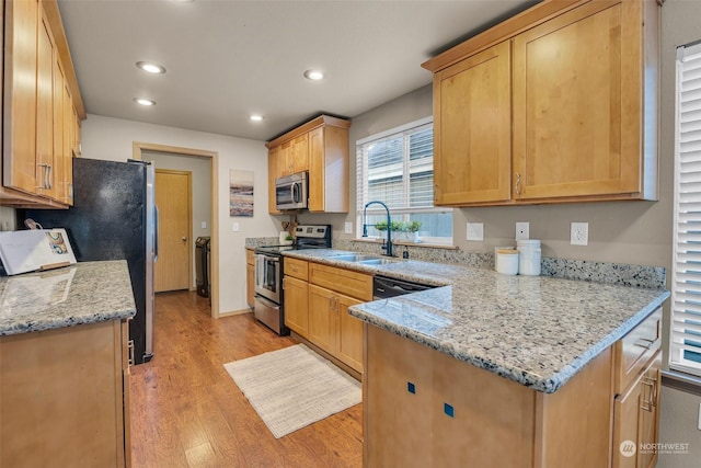 kitchen featuring light stone counters, appliances with stainless steel finishes, light hardwood / wood-style floors, and sink