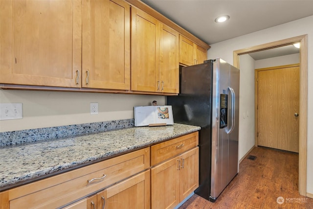 kitchen with light stone countertops, stainless steel fridge, and dark hardwood / wood-style flooring