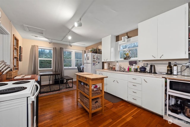 kitchen with white appliances, dark hardwood / wood-style flooring, and white cabinets