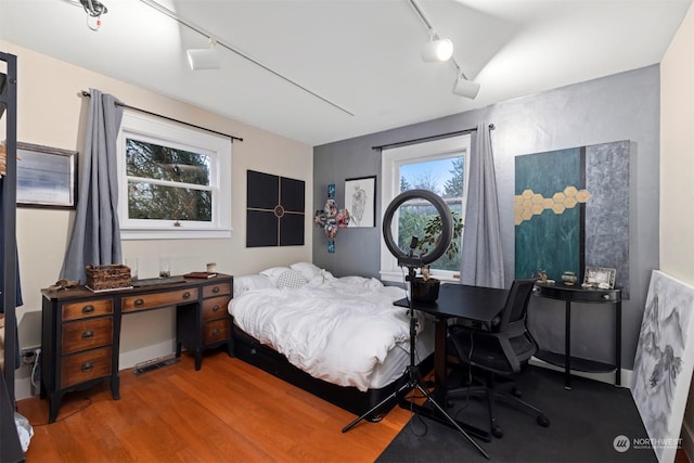 bedroom featuring hardwood / wood-style floors and track lighting