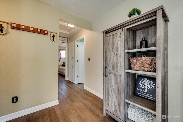 corridor featuring hardwood / wood-style flooring, a barn door, and a textured ceiling