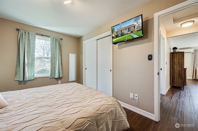 bedroom featuring an AC wall unit, dark hardwood / wood-style floors, and a closet