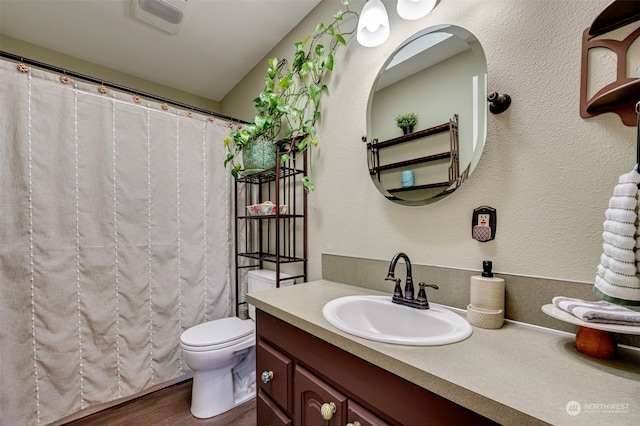 bathroom with wood-type flooring, vanity, and toilet