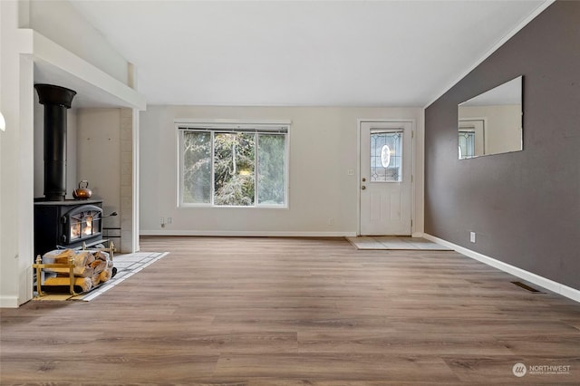 interior space with lofted ceiling, light hardwood / wood-style flooring, and a wood stove