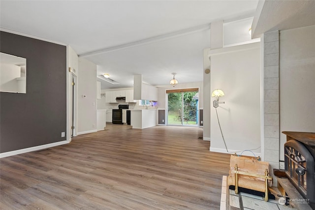 living room with lofted ceiling, hardwood / wood-style floors, sink, and a wood stove