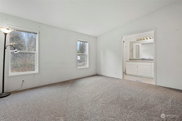 spare room with lofted ceiling, sink, and light colored carpet