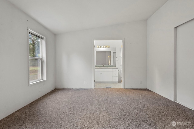 carpeted spare room with lofted ceiling and sink