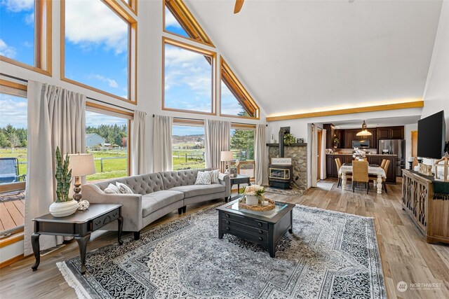 living room featuring light hardwood / wood-style flooring, high vaulted ceiling, and a wood stove