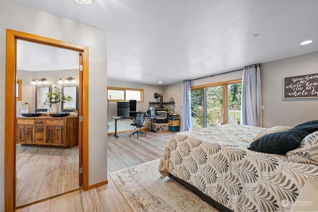 bedroom with multiple windows, connected bathroom, access to exterior, and light wood-type flooring