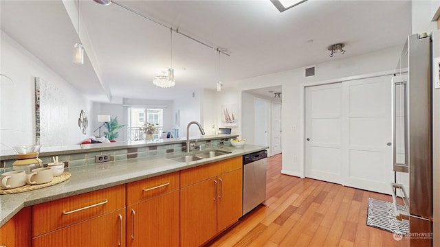 kitchen with pendant lighting, sink, light hardwood / wood-style flooring, and stainless steel dishwasher