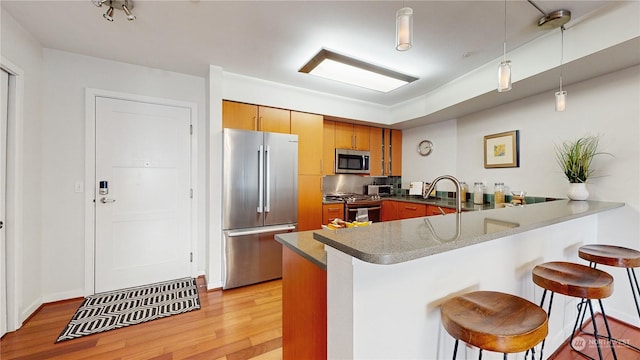 kitchen with stainless steel appliances, a kitchen breakfast bar, kitchen peninsula, and hanging light fixtures