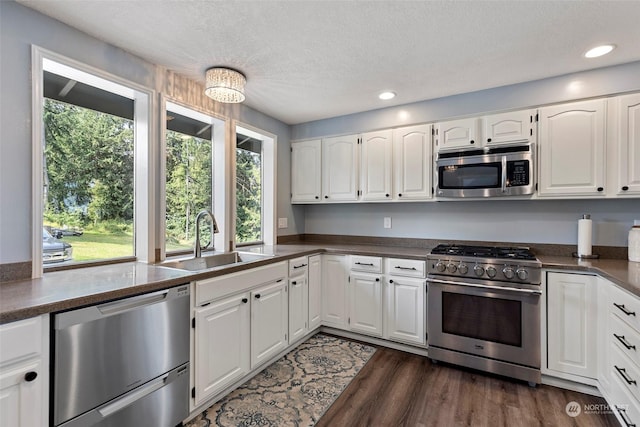 kitchen featuring sink, appliances with stainless steel finishes, dark hardwood / wood-style floors, a textured ceiling, and white cabinets