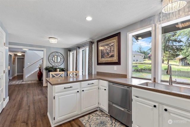 kitchen featuring sink, stainless steel dishwasher, dark hardwood / wood-style flooring, kitchen peninsula, and white cabinets