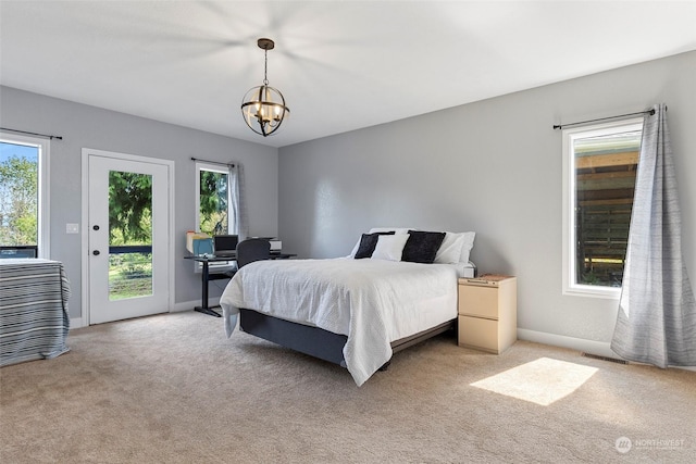 carpeted bedroom with an inviting chandelier and access to exterior