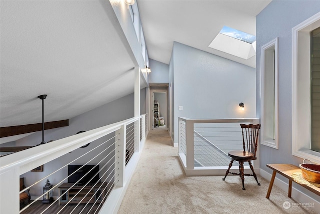 hall featuring light colored carpet and vaulted ceiling with skylight