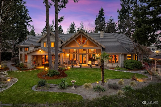 back house at dusk with a yard and a patio area