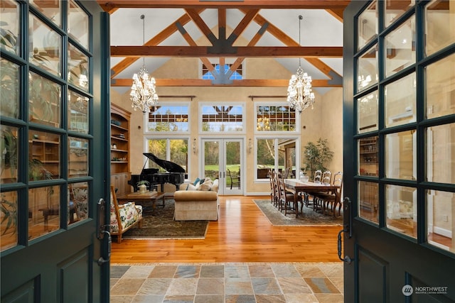 sunroom / solarium featuring vaulted ceiling, french doors, and a chandelier