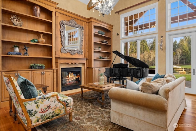 sitting room with a notable chandelier, built in shelves, wood-type flooring, and a high ceiling