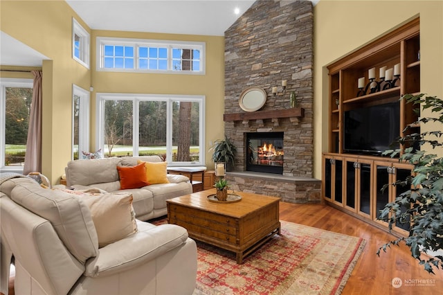 living room featuring a fireplace, high vaulted ceiling, and light wood-type flooring