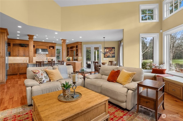 living room with plenty of natural light, light hardwood / wood-style floors, a high ceiling, and ornate columns