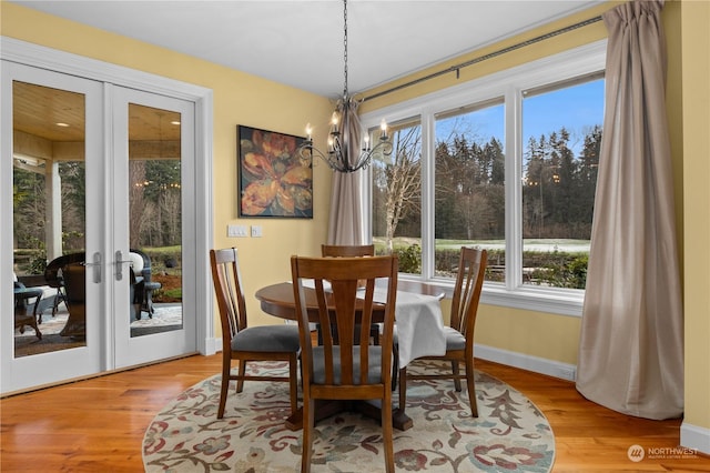 dining space featuring french doors, an inviting chandelier, and light hardwood / wood-style floors