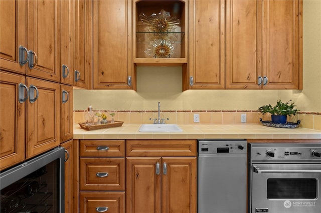 kitchen with stainless steel oven, tile countertops, beverage cooler, and sink